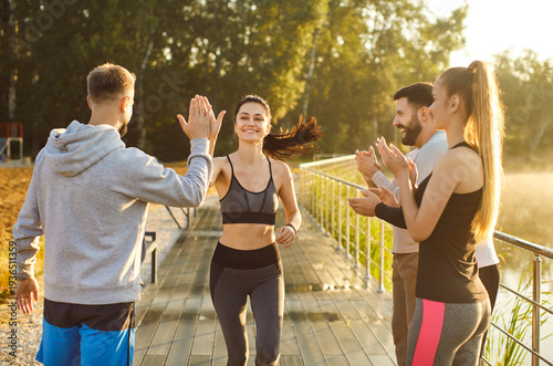 Bild auf Leinwand Team of people high fives together during outdoor fitness workout, boosting sport teamwork, enhancing training effort, uniting in fitness joy, engaging in a vibrant open-air exercise setting
