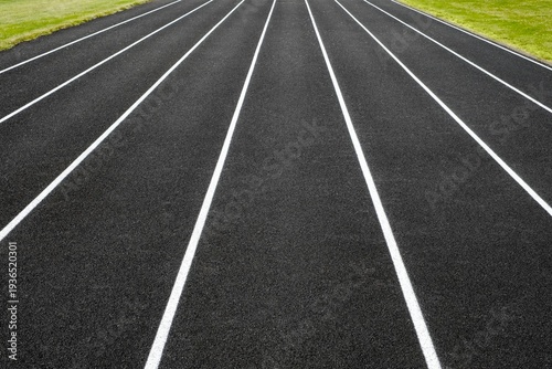 Symmetrical view of white-lined running lanes on a black asphalt track - a clean, minimalistic image symbolizing speed, competition
