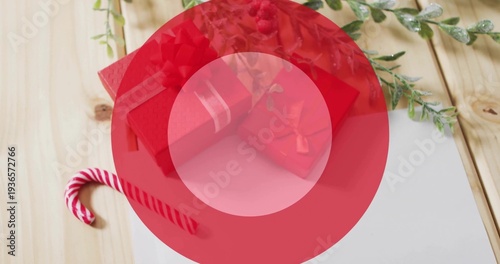 Displaying red gift boxes with ribbons on light wooden tabletop, featuring candy cane, white card