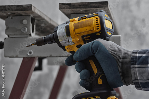 Fotografi Worker using cordless impact driver to fasten metal structure
