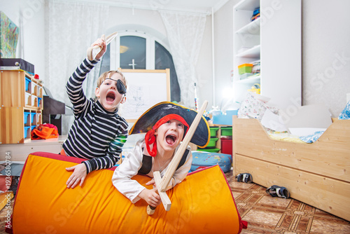 Children playing pirates in costume at home interior