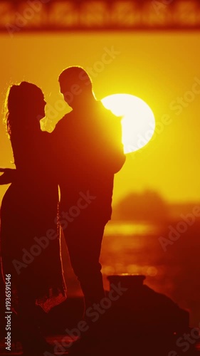 Silhouette of couple embracing at sunset - dancing near river bridge