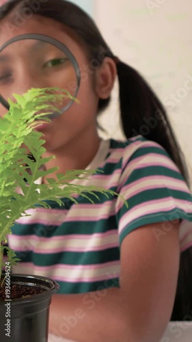 Vertical video: Using magnifier, student in striped shirt leaning at school, studying fern closely