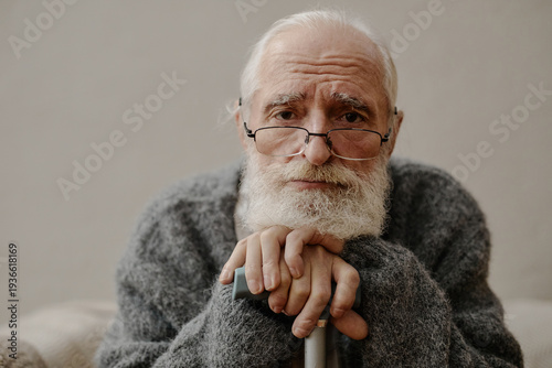 Billede på lærred Portrait of senior Caucasian man with beard and glasses resting hands on walking