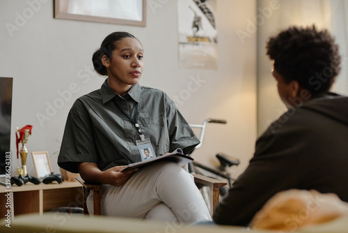 Photography Black young adult woman social worker holding clipboard engaging in conversation