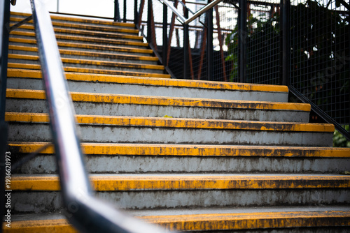 Urban pedestrian bridge stairs with yellow safety stripes