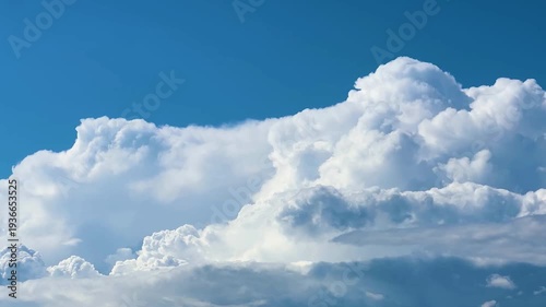 Majestic white cumulus clouds are forming and growing against a clear blue sky background