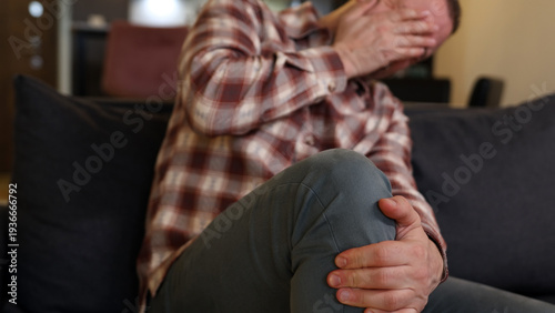 Man at home holding painful injured knee.