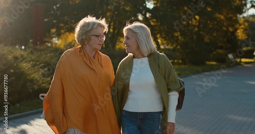 Senior women friends walking together in a sunny autumn park