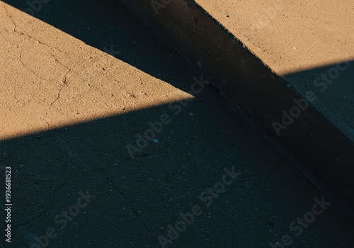 Diagonal lines and sharp geometry formed by sunlight creating strong contrast. Minimalist interplay of light and dark on a rough surface ,geometric ,pattern ,wall