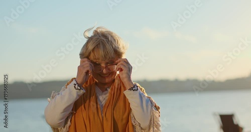 Happy senior woman wearing eyeglasses and smiling at sunset