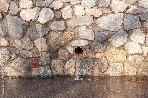 outdoor rainwater drainage hole with green moss growing on it