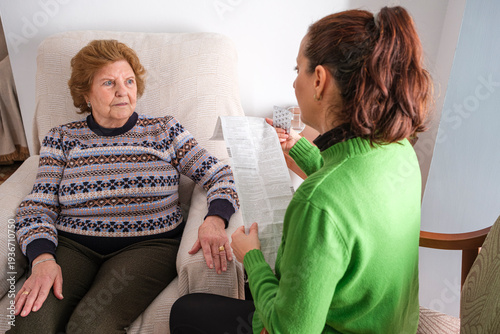 A woman reads the leaflet of a medicine to an elderly woman.