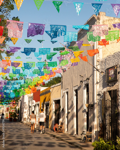 Colorful papel picado flags adorn a charming street in Valladolid, Mexico