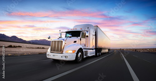 White semi truck / lorry and highway / road at sunset - transportation background. Beautiful sky and romatic feel. White body / side of the truck. Wide angle / panoramic view.