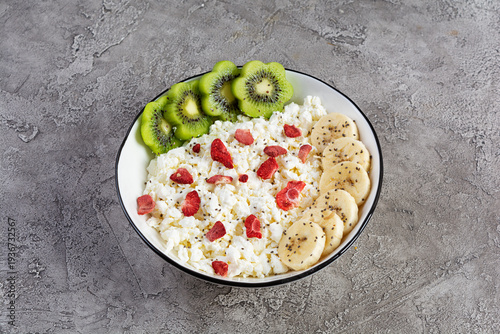 Healthy breakfast bowl with cottage cheese, fresh kiwi, banana slices and dried strawberries