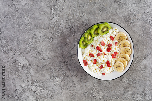 Healthy breakfast bowl with cottage cheese, fresh kiwi, banana slices and dried strawberries