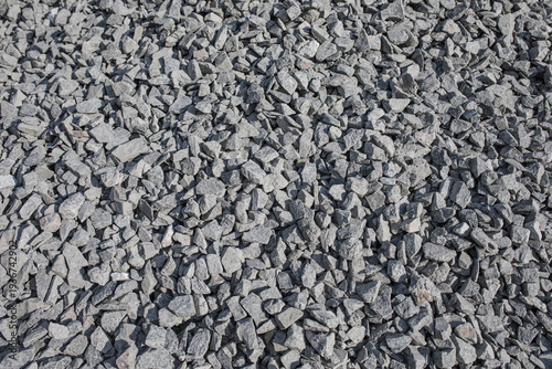 Background texture of grey crushed granite stone gravel pile used for construction industry and road building
