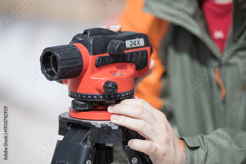 Surveyor adjusting optical level on tripod at construction site measuring ground elevation for engineering project
