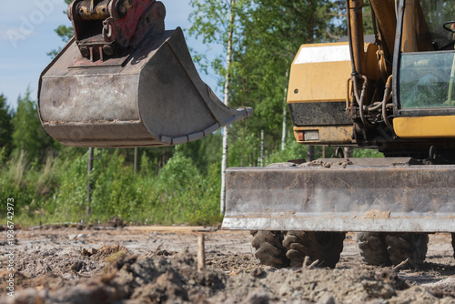 Excavator bucket digging soil at construction site during road building with heavy machinery working outdoors