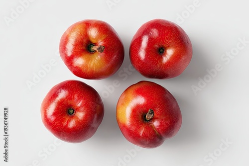 Four, vibrant, round, red fruits arranged on a plain white surface