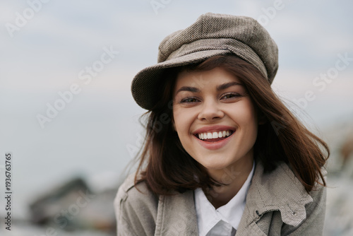 Photography Smiling young woman with long brown hair wearing a grey newsboy cap and coat outdoors
