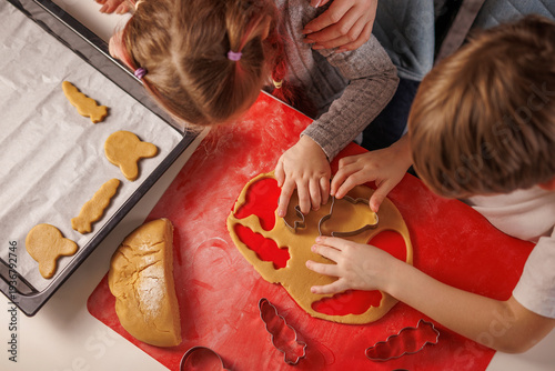 Children preparing homemade cookies from dough to baking tray.
