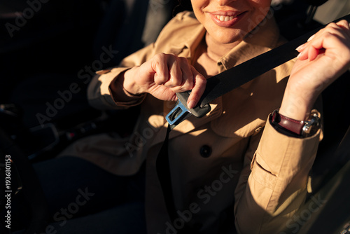 Fotografie Woman buckling up car seatbelt for road safety