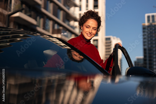Woman smiling opening car door in city setting