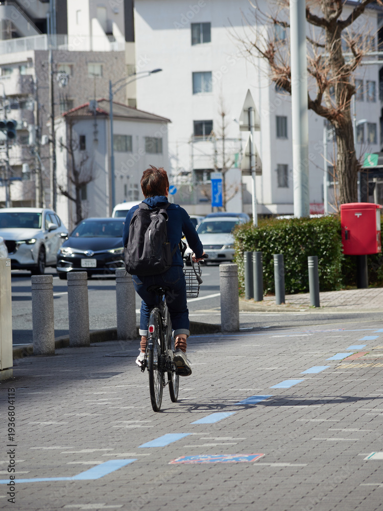 Fototapeta premium 春の昼の名古屋の街で自転車を乗る男性と町並みの風景