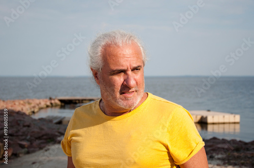 Enjoying time by sea in retirement. Senior lifestyle. Mature man by ocean horizon during sunset. Authentic masculine style. Retired man enjoying peaceful seaside view