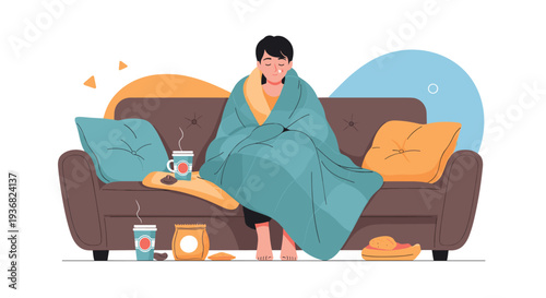 Sick woman wrapped in a thick blue blanket sitting on a sofa with hot drinks and medication while recovering from a fever or flu at home.