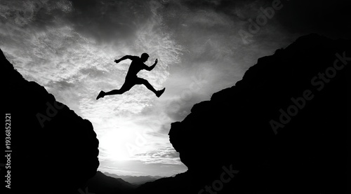 Silhouette of a person leaping across a chasm under a cloudy sky