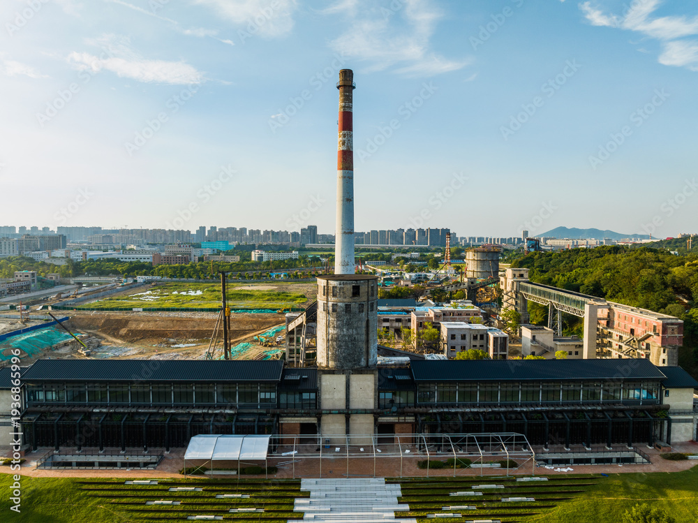 Obraz premium Industrial Heritage Factory with Striped Chimney and Urban Skyline