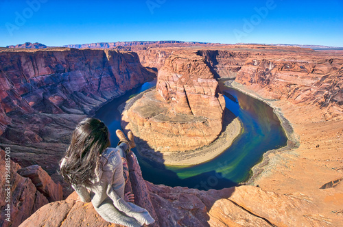 A woman is sitting on a rock overlooking a river