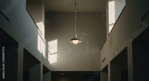 Interior view of a hallway with a hanging light fixture and sunlit high walls