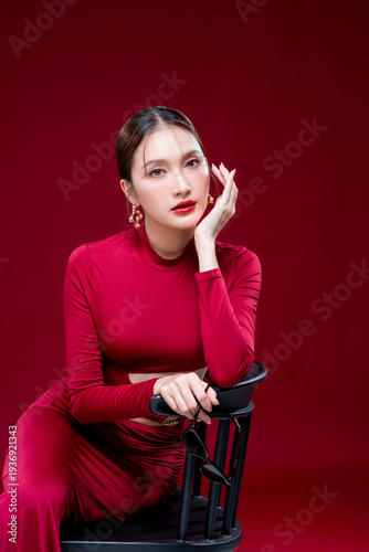 Фотография Elegant Asian fashion woman wearing a stylish red dress sitting on a chair again