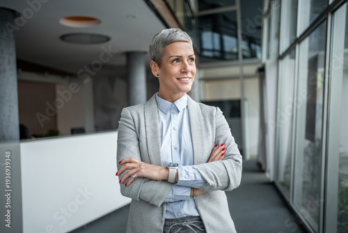 Wallpaper Mural Confident businesswoman smiling with arms crossed in modern office Torontodigital.ca