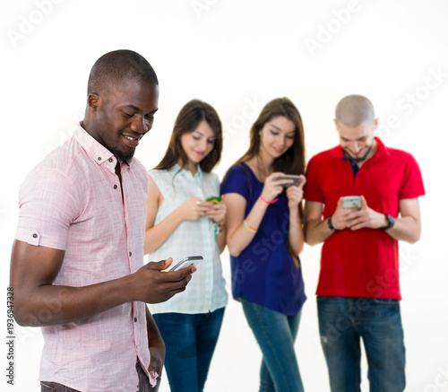 Bild auf Leinwand Group of multiethnic young friends standing together and using their smartphones