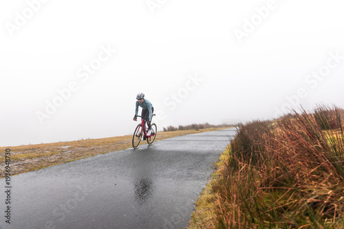 Young caucasian woman riding a bike on the mountains on a rainy day, at the Arzamendi mountain -Basque Country-.