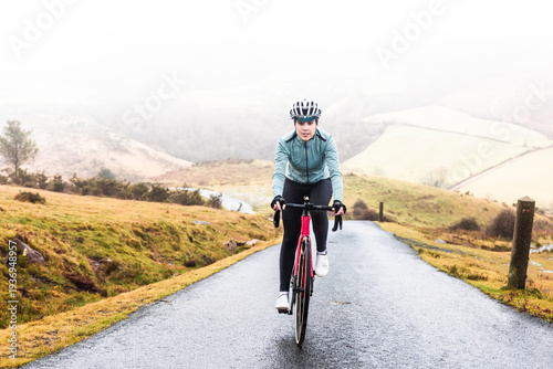 Young caucasian woman riding a bike on the mountains on a rainy day, at the Arzamendi mountain -Basque Country-.