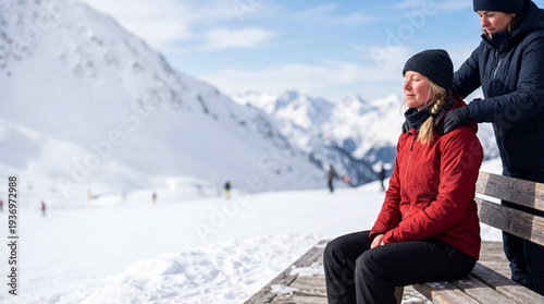 Woman giving shoulder massage to another woman sitting on bench in snowy mountain resort. Female friends relaxing during winter vacation. Peaceful outdoor rest and wellness concept.