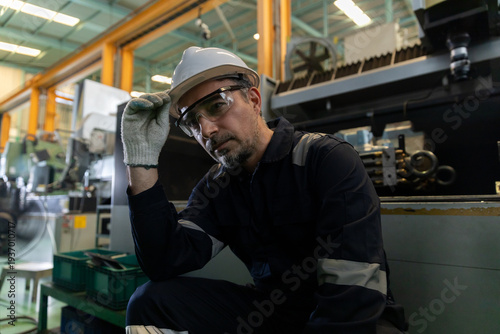 Εκτύπωση καμβά Factory maintenance technician resting beside heavy machinery, wearing hardhat, safety glasses and glove