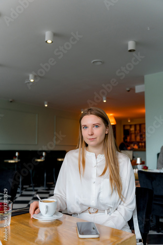 Young Woman Drinking Coffee in Modern Cafe Interior