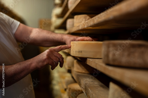 Cheesemaker affineur cheese aging cellar shelves wheels aging traditional craftsmanship expertise dairy production Italian selection quality control