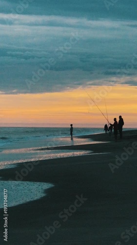 Fishermen Standing on Shore Casting Rod into Sea at Dusk on the Beach a Summer Afternoon