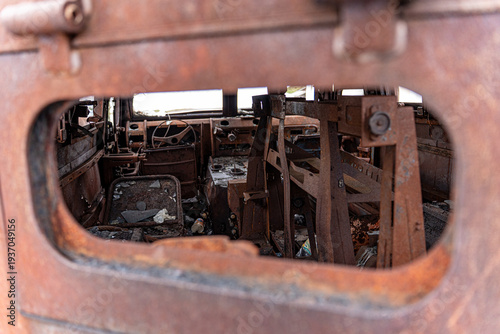 View of the interior of a rusted, derelict vehicle, a stark reminder of conflict, framed by a corroded opening, Kyiv, Kyiv, Ukraine.