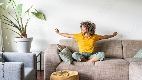 Happy afro american woman relaxing on the sofa at home - Smiling girl enjoying day off lying on the couch - Healthy life style, good vibes people and new home concept