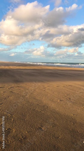 Windy Beach with Blowing Sand and Rough Ocean Waves Under Cloudy Sky