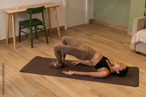 Foto Athletic woman performing pilates bridge exercise on mat focusing on glute activ